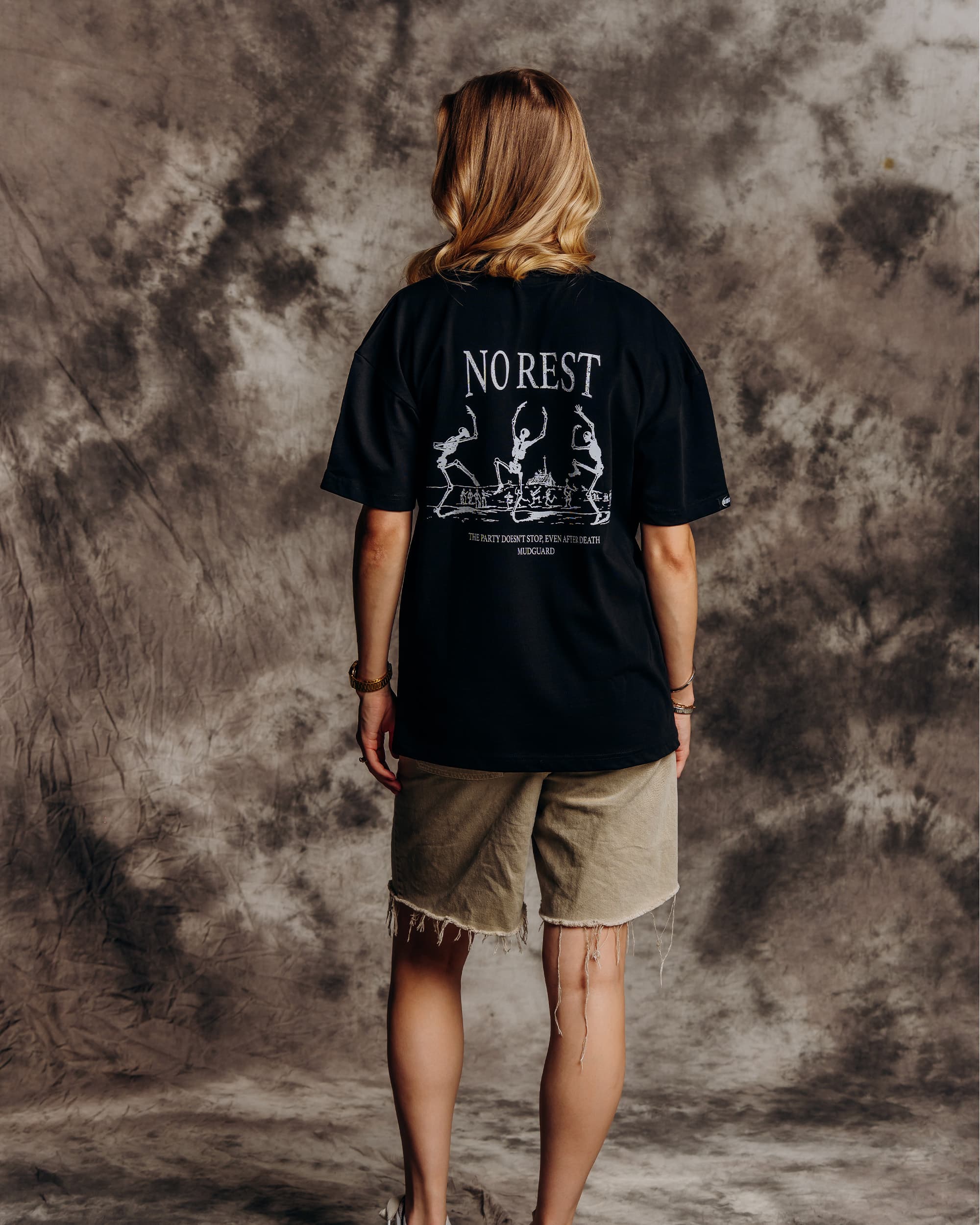Oversized black graphic t-shirt model back view showing skeleton print